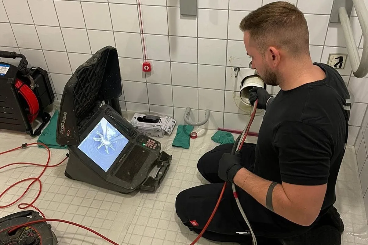 Kanalinspektion: Mitarbeiter des Partnerbetriebs P&N führt die Kamera über einen Zugang im Sanitärraum in die Abwasserleitung