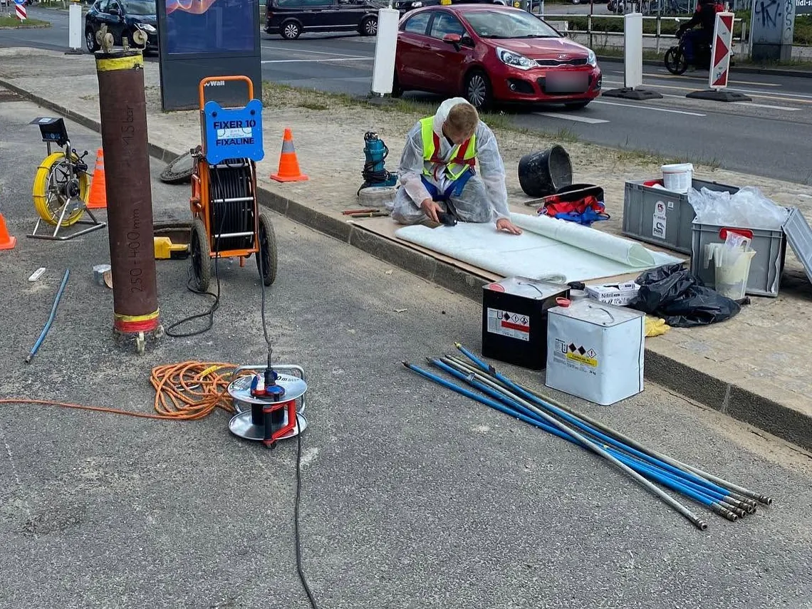 Monteur von P&N schneidet an einer Straßenbaustelle Linermaterial für eine punktuelle Reparatur zu